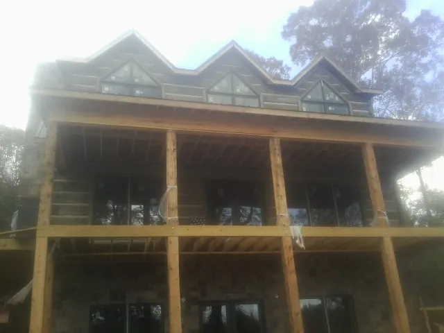 Dormers and porch framing on a large log home under construction — Roof Coating work by our crew in Vandiver