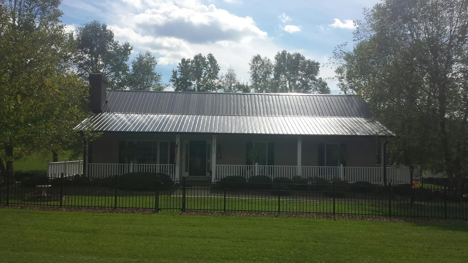 Gray metal roof on a brick ranch with a full width front porch — Gutter Guard Installation work by our crew in Vandiver