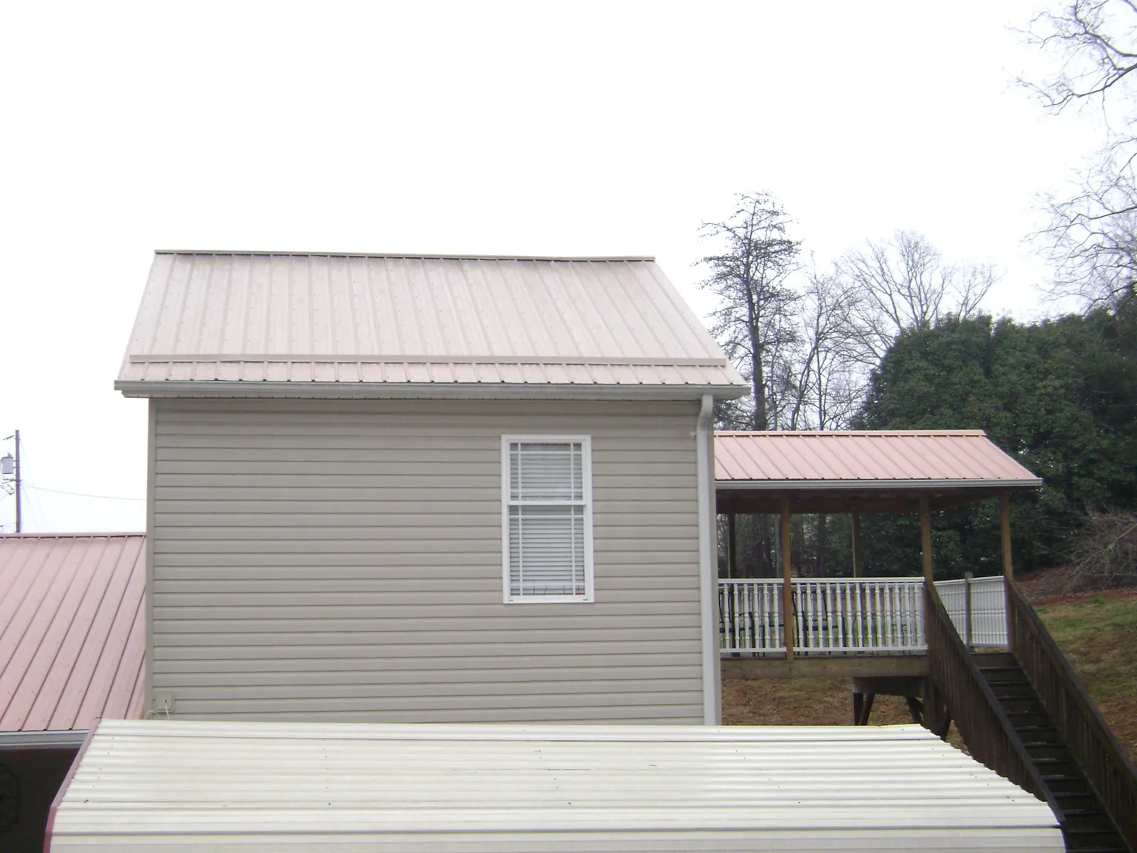 Tan metal roofs on a two story addition and attached porch, from a Roof Replacement job in Vandiver