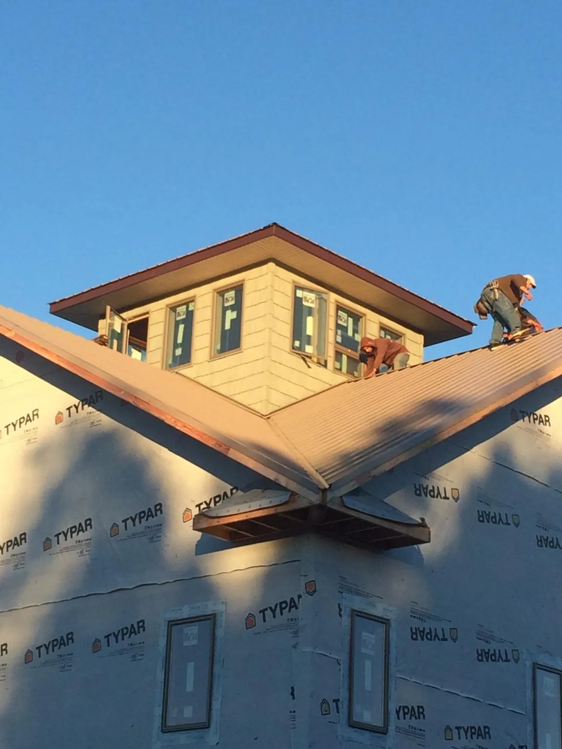 Roofers working around a rooftop cupola on a new metal roof at sunset — Roof Waterproofing in Vandiver by Roofing Brothers